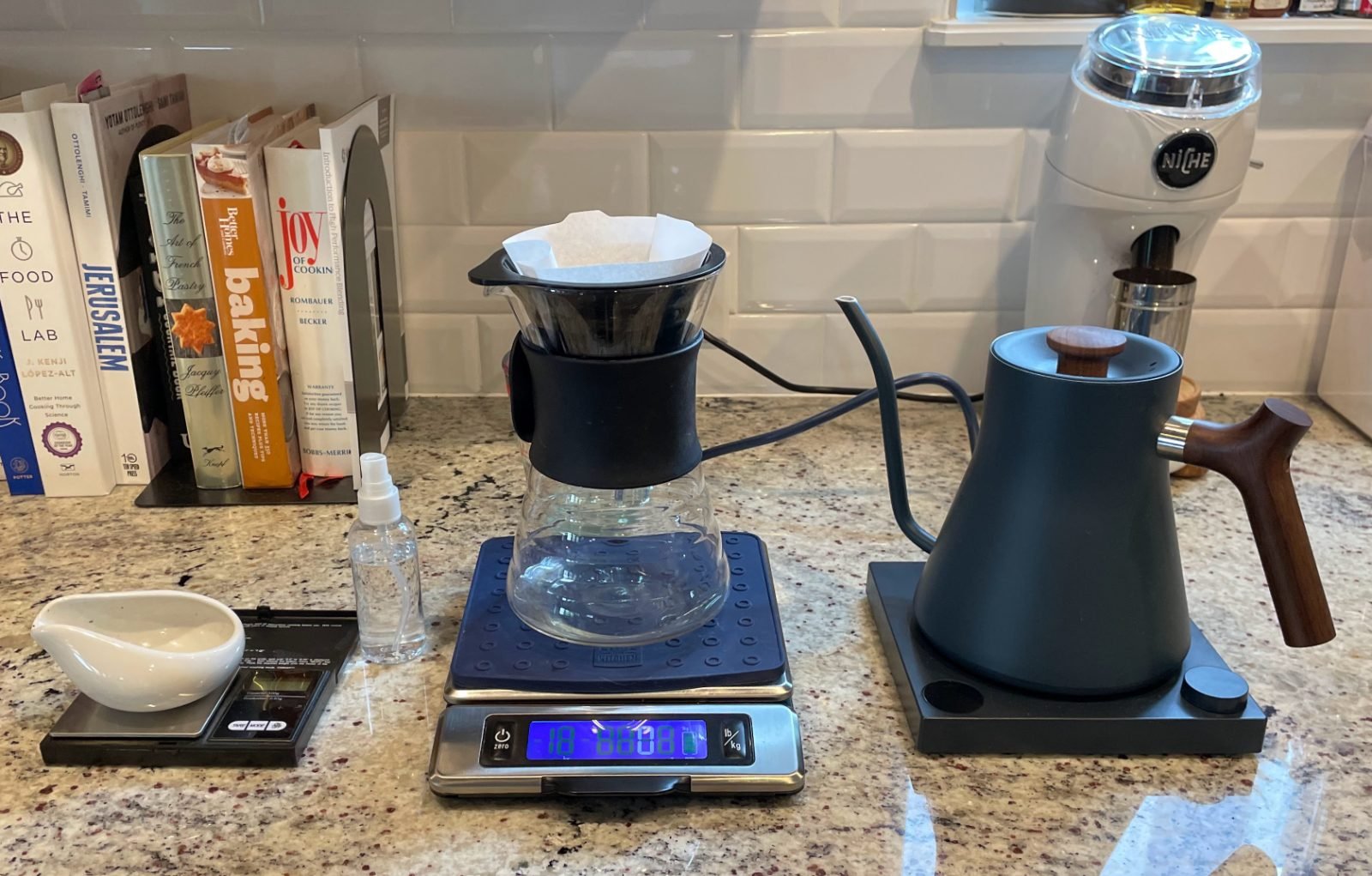 A full pour-over setup with dripper, gooseneck kettle, scale, and grinder